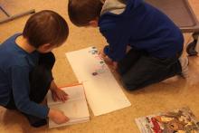 Chłopcy czytają książkę pomysłu Jasia. 